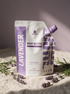 Kokoualush Lavender Body Butter pouch on oatmeal linen with fresh lavender sprigs