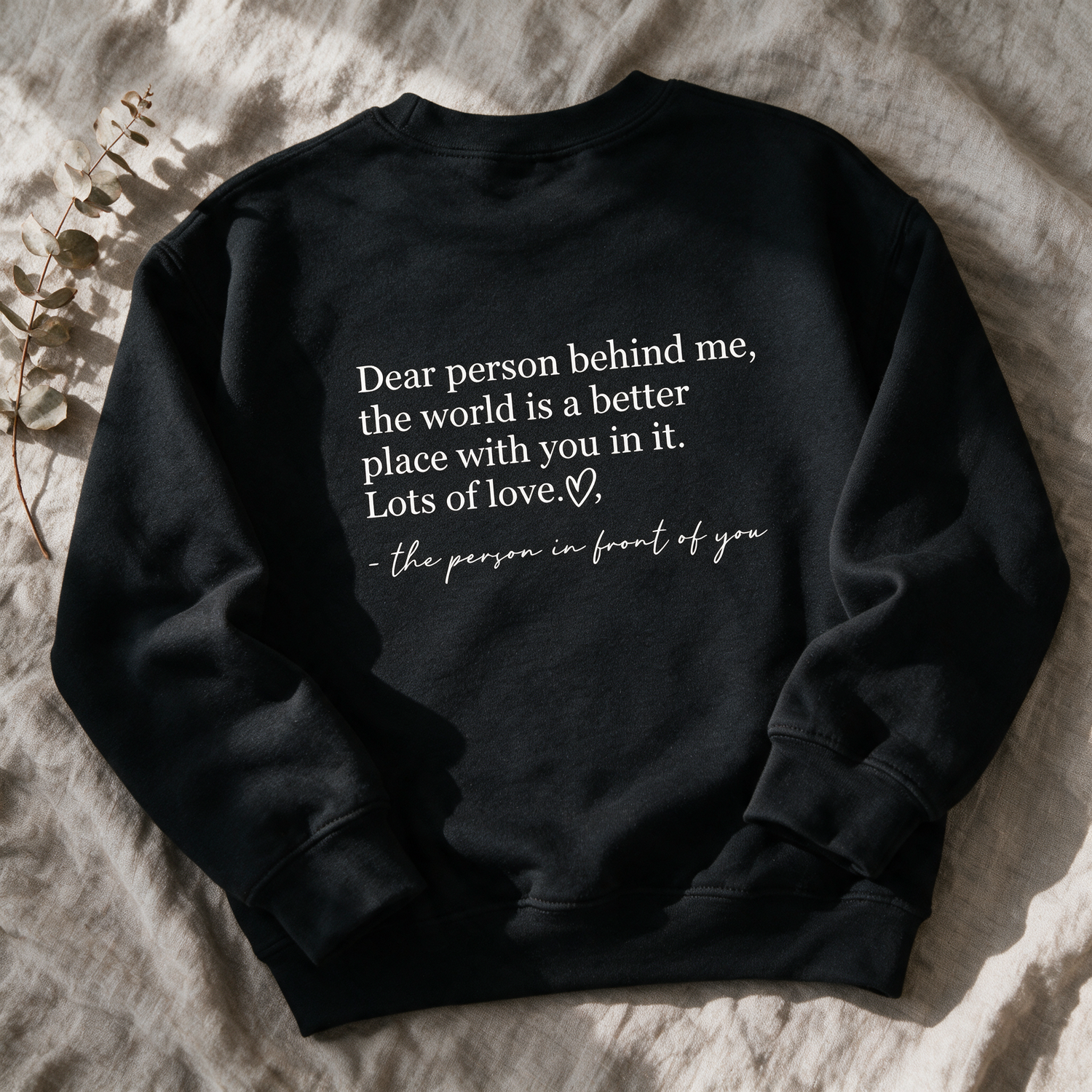 Kokoualush Be Kind black crewneck flat-lay showing the Dear person behind me back print on linen