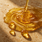 Macro texture of golden turmeric face and body oil with gold flecks and beaded droplets