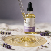 Kokoualush Lavender Relaxing Body Oil pale gold droplet crown splash with lavender sprigs on linen