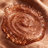 Macro texture of bronze shimmer body glow oil densely packed with copper glitter