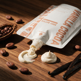 How to use Kokoualush Vanilla Cocoa body butter: pouch squeezing a butter swirl with cocoa beans