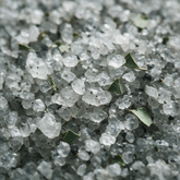 Macro of grey mineral bath salts with charcoal flecks and eucalyptus
