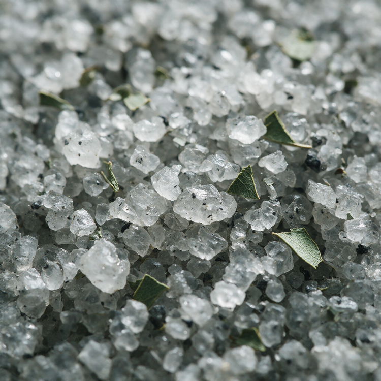 Macro of grey mineral bath salts with charcoal flecks and eucalyptus