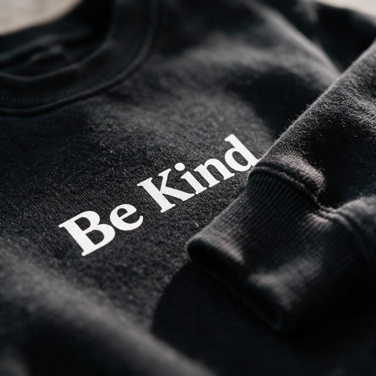 Macro of the black crewneck fleece and Be Kind print detail