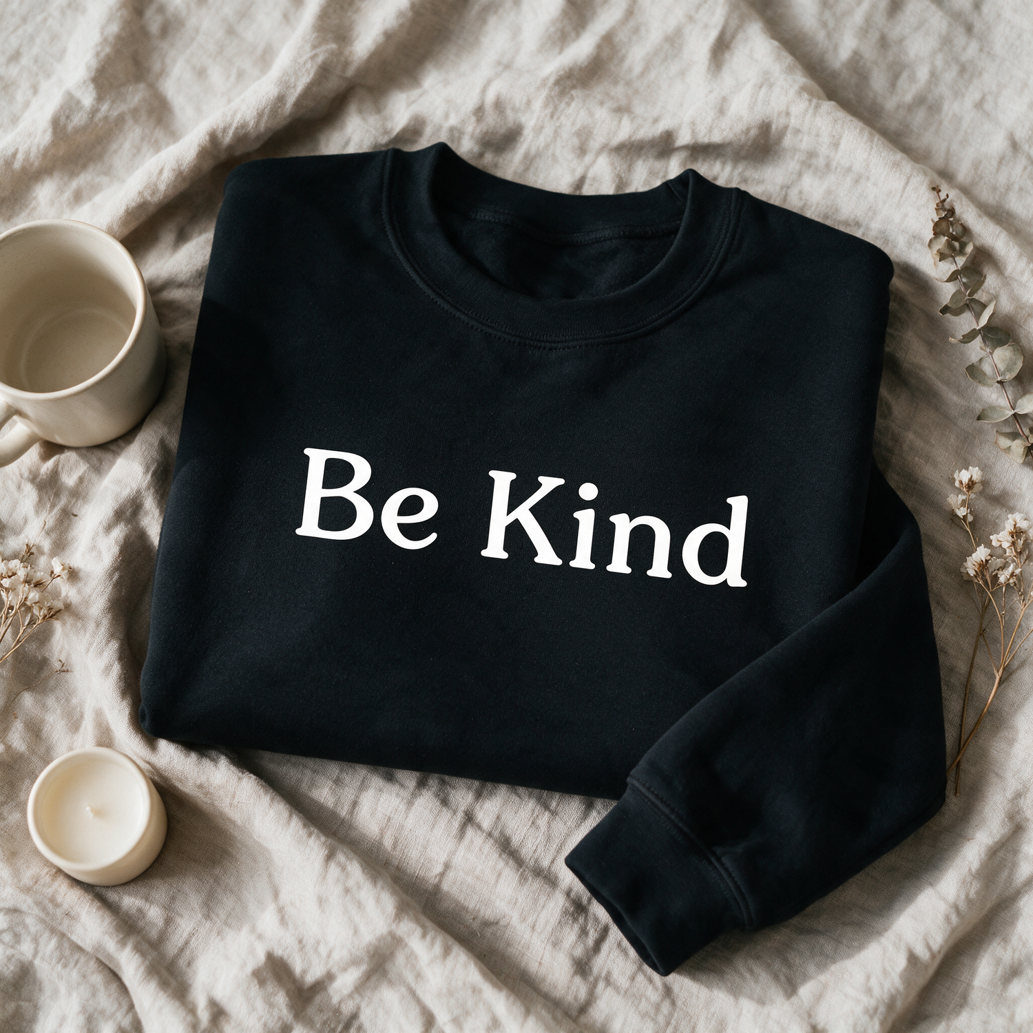 Be Kind black crewneck folded and styled with self-care props