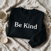 Be Kind black crewneck folded and styled with self-care props