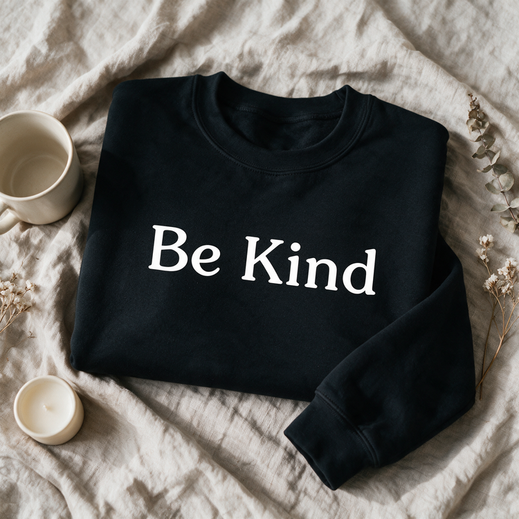Be Kind black crewneck folded and styled with self-care props