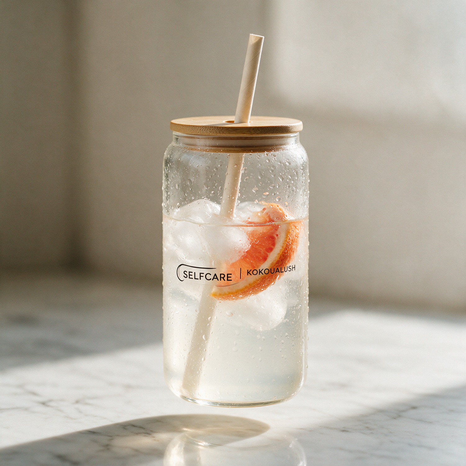 Kokoualush Selfcare affirmation glass with an iced drink and glass straw